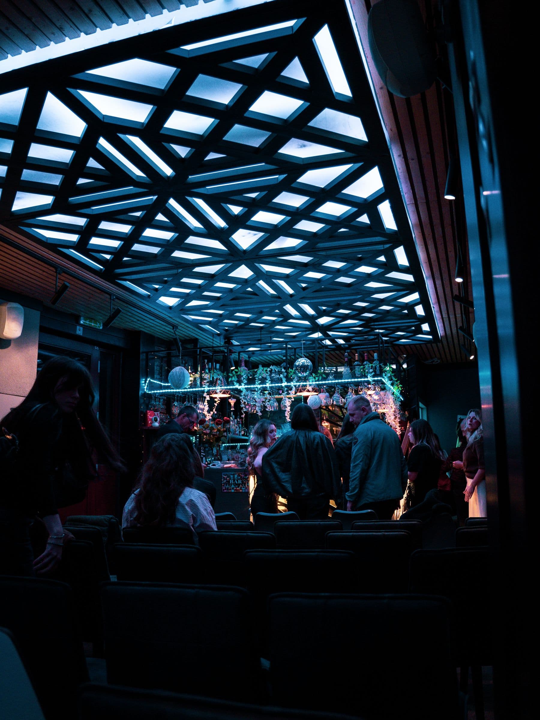 Guests standing at the bar under the glowing ceiling.