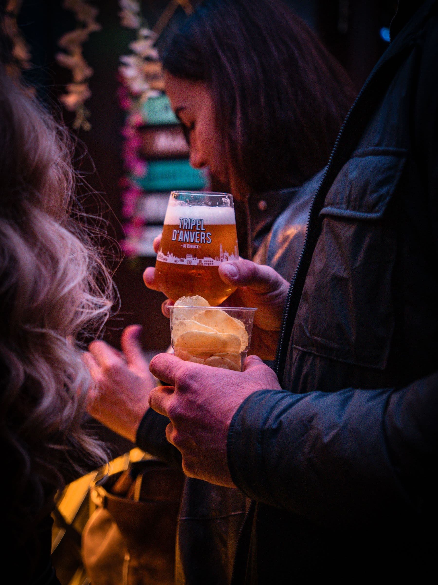 A glass of beer and a bowl of crisps held at the bar.