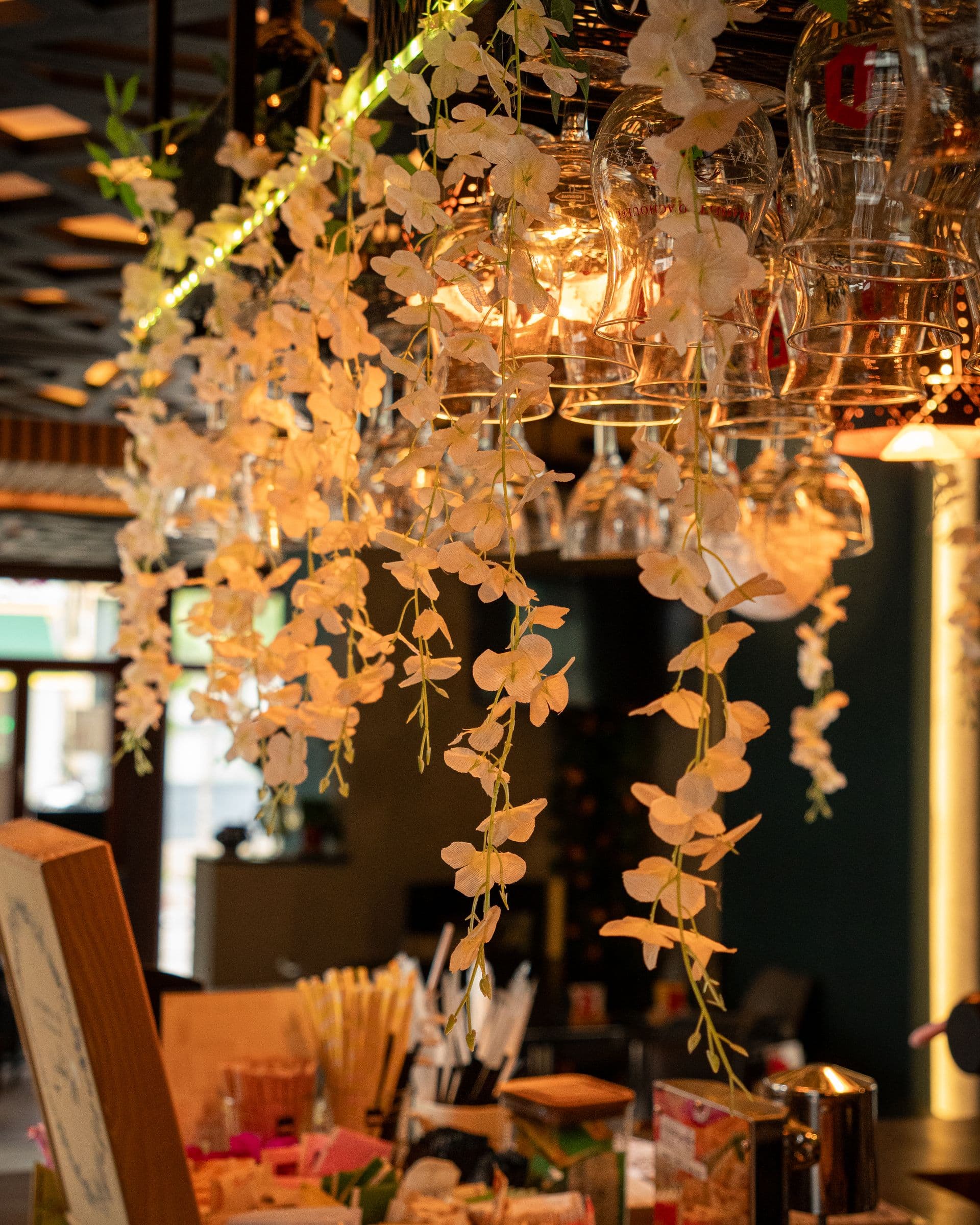 Wine glasses and white blossom hanging over the counter.
