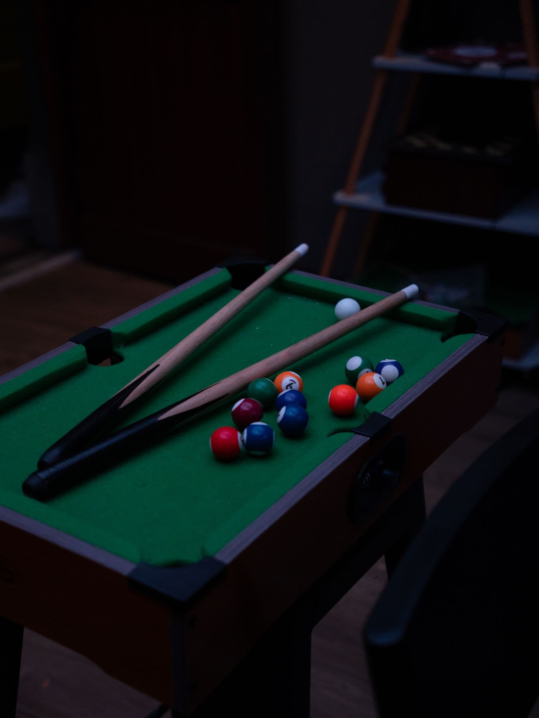 A small pool table with cues and balls racked.