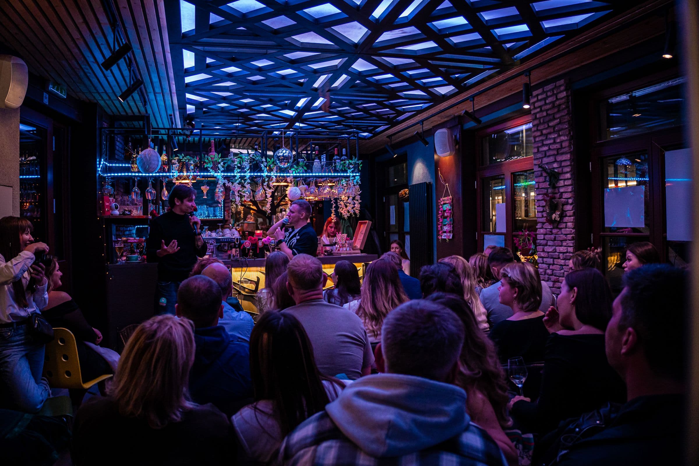 The room at night under the lit geometric ceiling, full of guests.